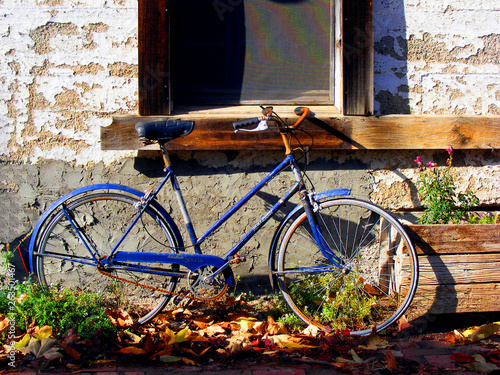 Blue bicycle rests against a rustc farmhouse building photo