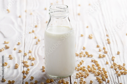 Non-dairy alternative Soy milk or yogurt in glass bottle on white wooden table with soybeans aside
