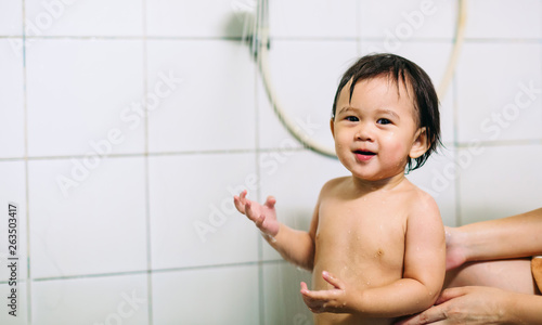 a baby smile and happy while bathing with her mother in the bath room.