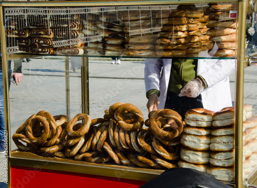 seller man behind traditional street cart vending with Turkish bagel (simit, gevrek) on streets of Istanbul, on sunny day, close up