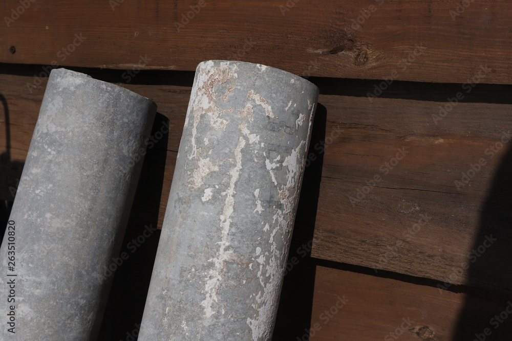 white and grey asbestos pipes by the wooden brown wall white and grey asbestos pipes by the wooden brown wall