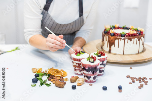 Decoration of the finished dessert. Pastry chef sprinkles confectionery with yellow powder. The concept of homemade pastry  cooking cakes.