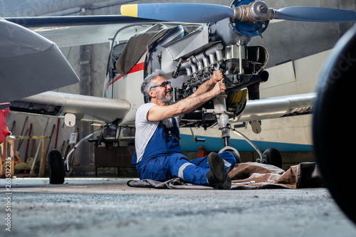 Aircraft mechanic repairs an aircraft engine in an airport hangar 