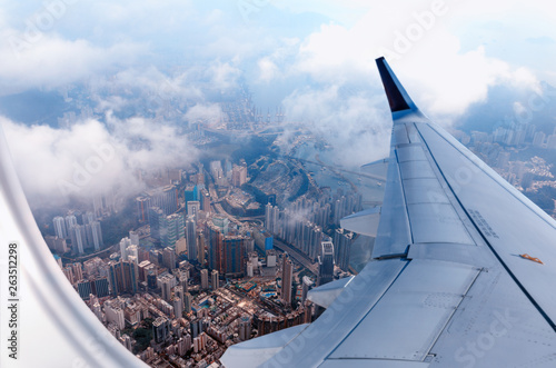 Plane to Hong Kong. Airplane window view at the skyscrapers. Overhead city view. Cityscape aerial. Concept of travel and air transportation..