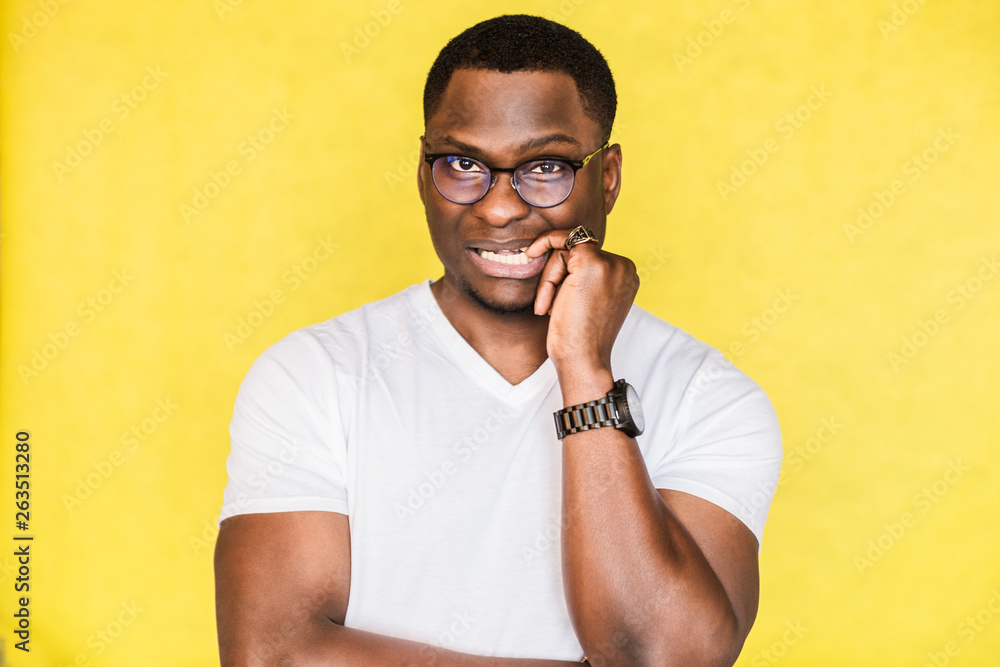 African American man feels anxious, bites finger nails in confusion. African American man feels anxious, bites finger nails in confusion.
