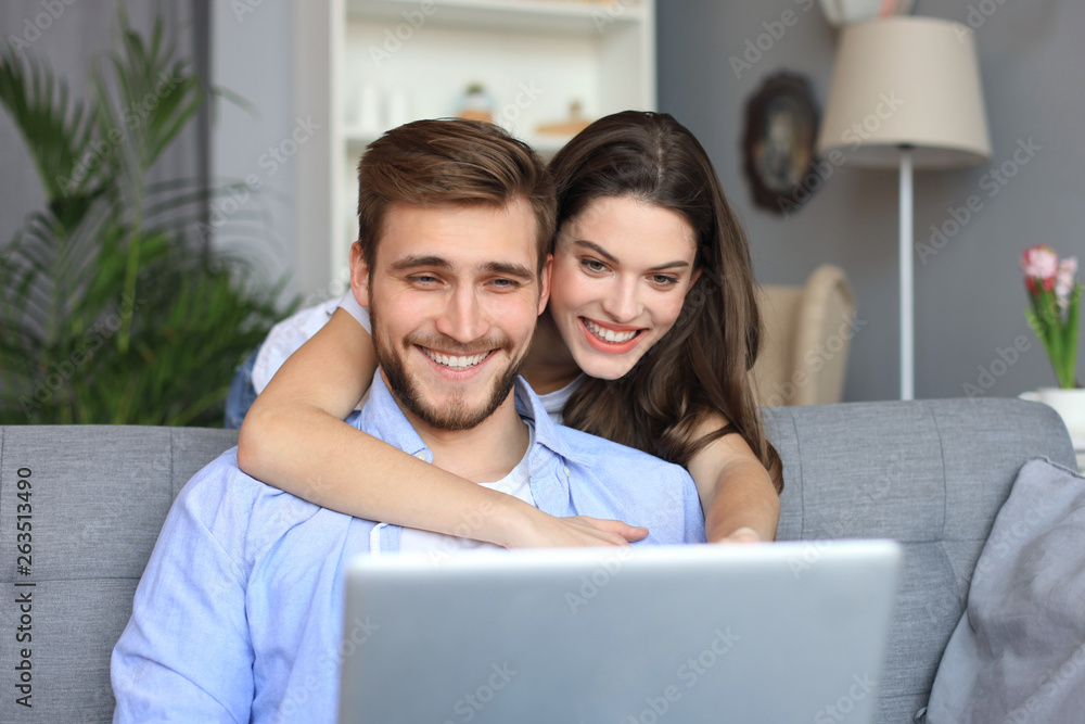 Young couple doing some online shopping at home, using a laptop on the sofa. Young couple doing some online shopping at home, using a laptop on the sofa.
