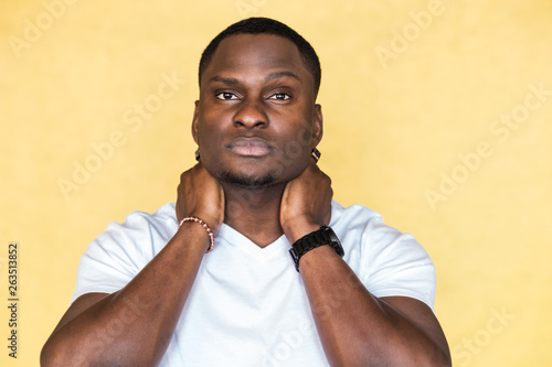 Attractive African American man keeps hands on neck.