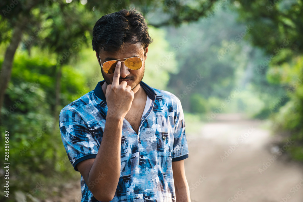 A young boy looking at camera wearing a golden sun glass and holding it by his finger A young boy looking at camera wearing a golden sun glass and holding it by his finger
