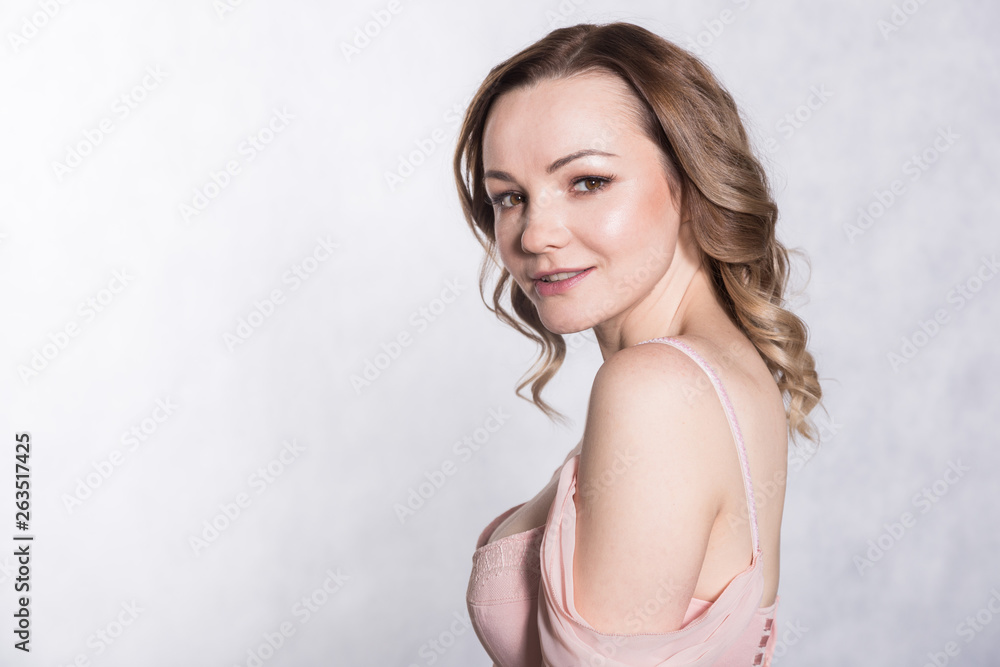 Portrait of beautiful young elegant female in pale pink wedding dress with big neckline, on a white background. Portrait of beautiful young elegant female in pale pink wedding dress with big neckline, on a white background.
