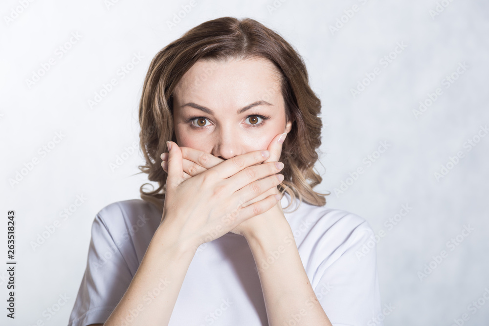 Surprised beautiful young woman covers mouth in shock. Surprised beautiful young woman covers mouth in shock.