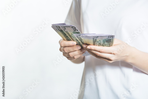 Pensive young woman counts us dollar money over white background.