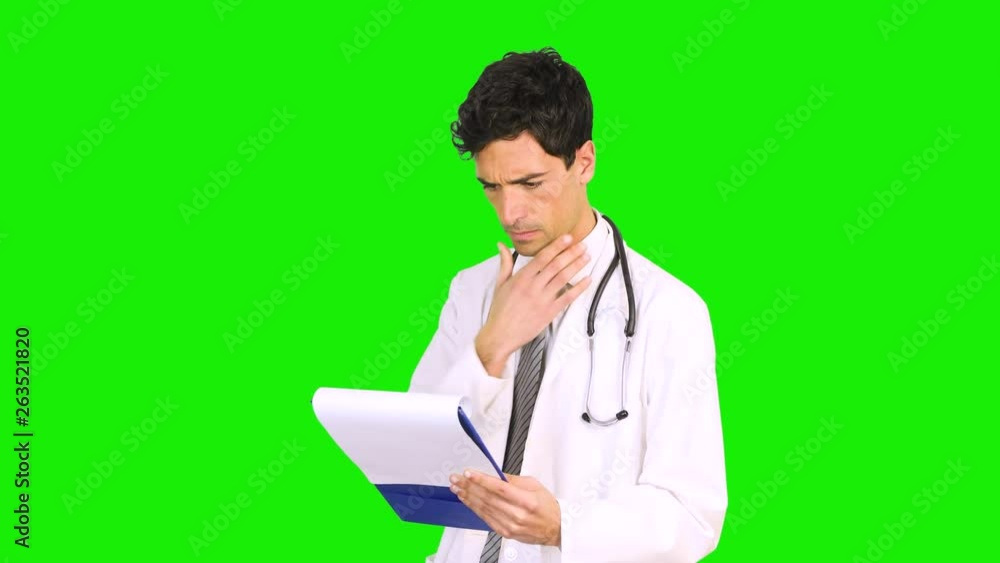 Young doctor reading a case history isolated on green screen chroma key background Young doctor reading a case history isolated on green screen chroma key background