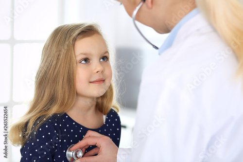Doctor examining a child patient by stethoscope. Cute baby girl at physician appointment. Medicine concept