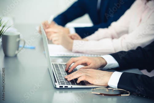 Group of business people working together in office. Man hands typing on laptop computer