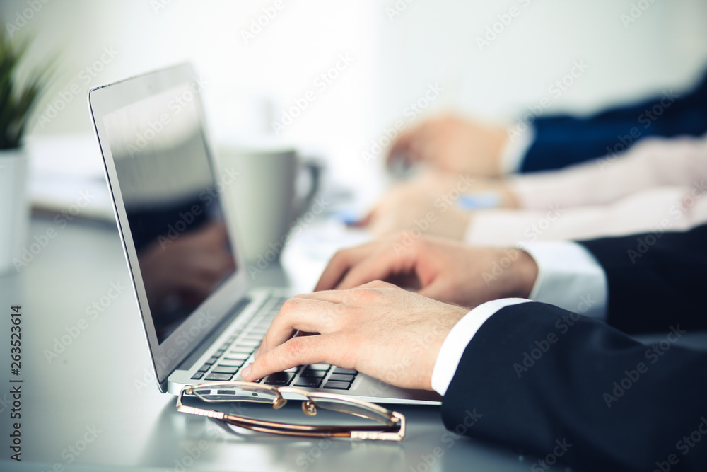 Group of business people working together in office. Man hands typing on laptop computer Group of business people working together in office. Man hands typing on laptop computer
