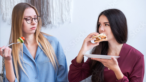 two girls eat their lunch  a woman on a diet  refuse junk food and eat salad. care about the health  nutrition of students.