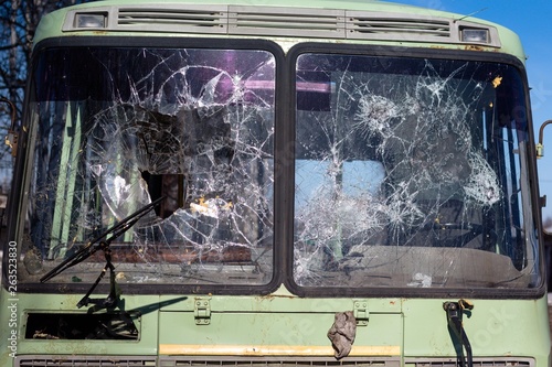 Bus glasses are heavily broken after car crashes on the road. The windows crashed when colliding at high speed.