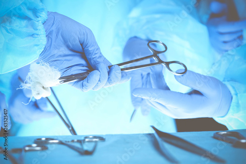 Surgeons hands holding surgical scissors and passing surgical equipment, close-up. Health care and veterinary concept