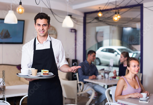 Waiter man is warmly welcoming guests