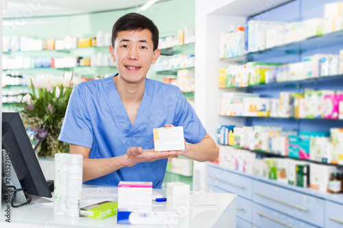  japanese specialist standing near table with cashbox in pharmacy
