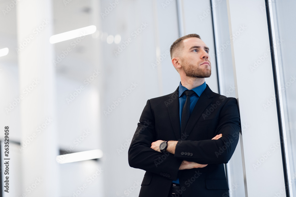 Portrait of young confident stylish business man with crossed hands near window. Portrait of young confident stylish business man with crossed hands near window.