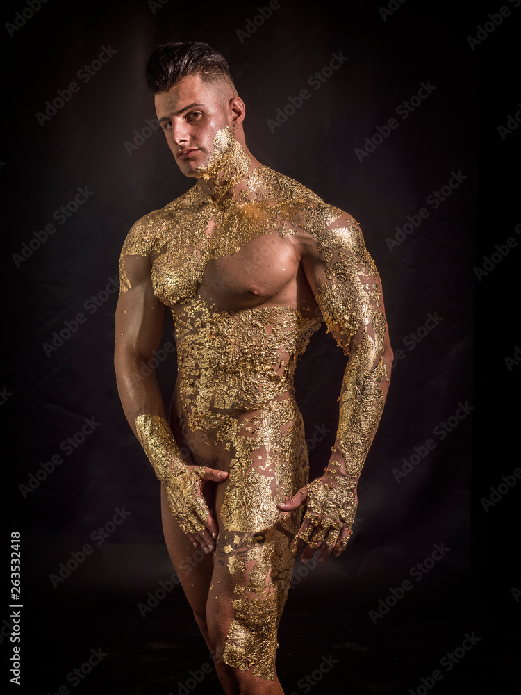 Muscular naked man covered with golden ing chin and looking down sensually  on black background Stock Photo | Adobe Stock