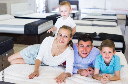 Father with mother and kids are testing quality of mattress