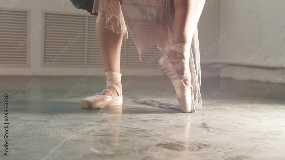 Close up of a ballet dancer s feet as she dancing in pointe shoes. Ballerina in stage long flowing dress shows classic ballet pas. Close up of a ballet dancer s feet as she dancing in pointe shoes. Ballerina in stage long flowing dress shows classic ballet pas.