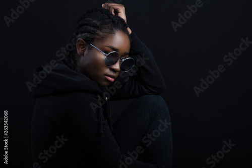 Cool african woman sitting with dark skin wearing round sunglasses