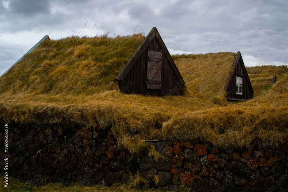 Scenic landscape view of tourist popular attraction/destination historical traditional Grenjadarstadur farm houses with turf roof, a church and cemetery nearby. Lake Myvatn, Iceland