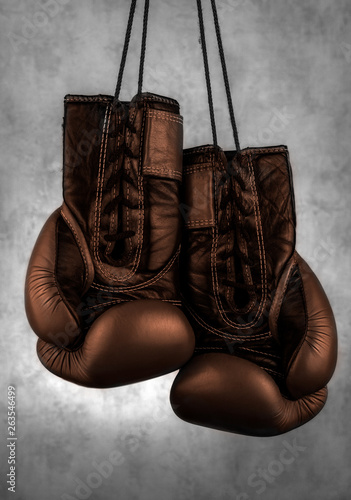  brown boxing gloves hanging on the wall, close-up.