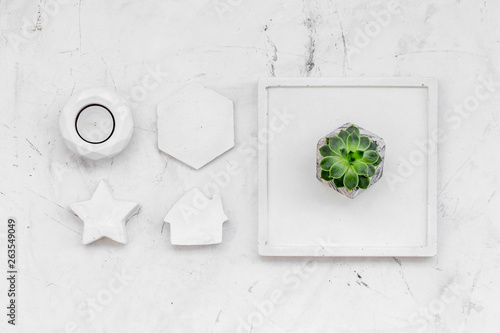 modern design of work desk with plant, candle, house and star figures on white marble background top view