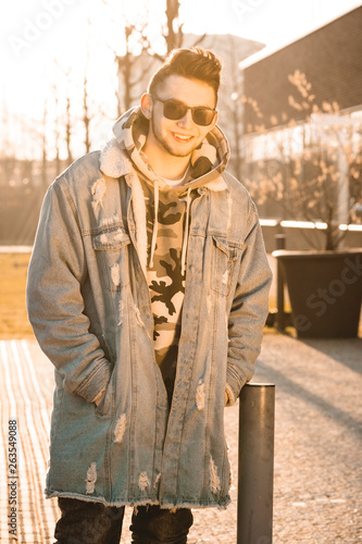 Fashionable handsome hipster man model with stylish sunglasses posing in the city at sunrise © Jan