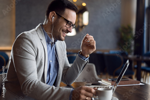 Happy young man listening to the music while working on a computer. photo