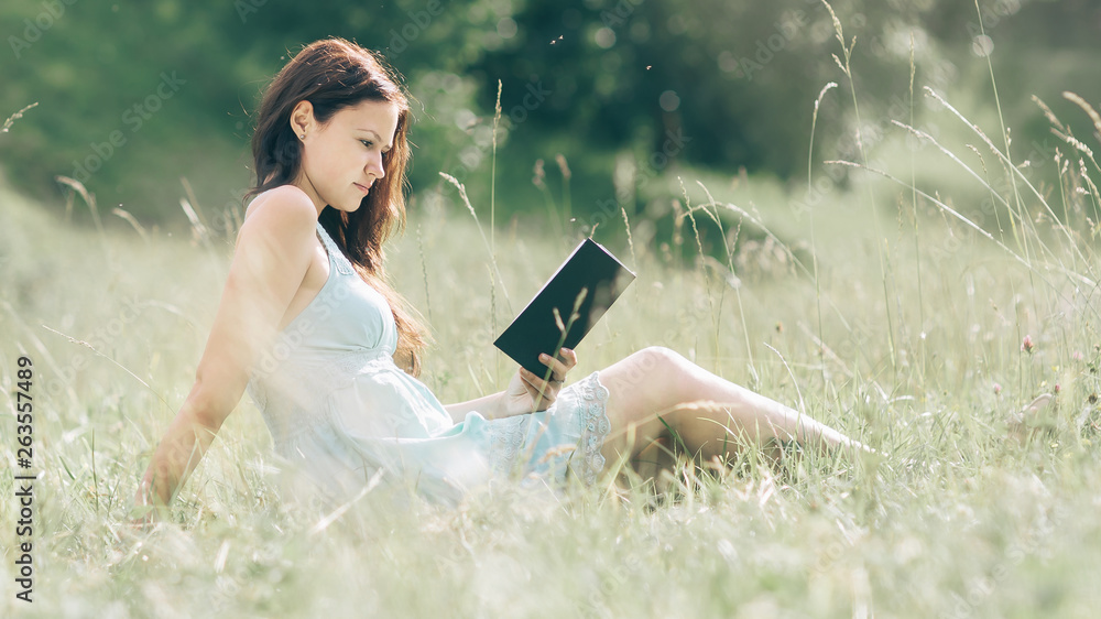 girl student reading a book sitting on the lawn on a summer day girl student reading a book sitting on the lawn on a summer day