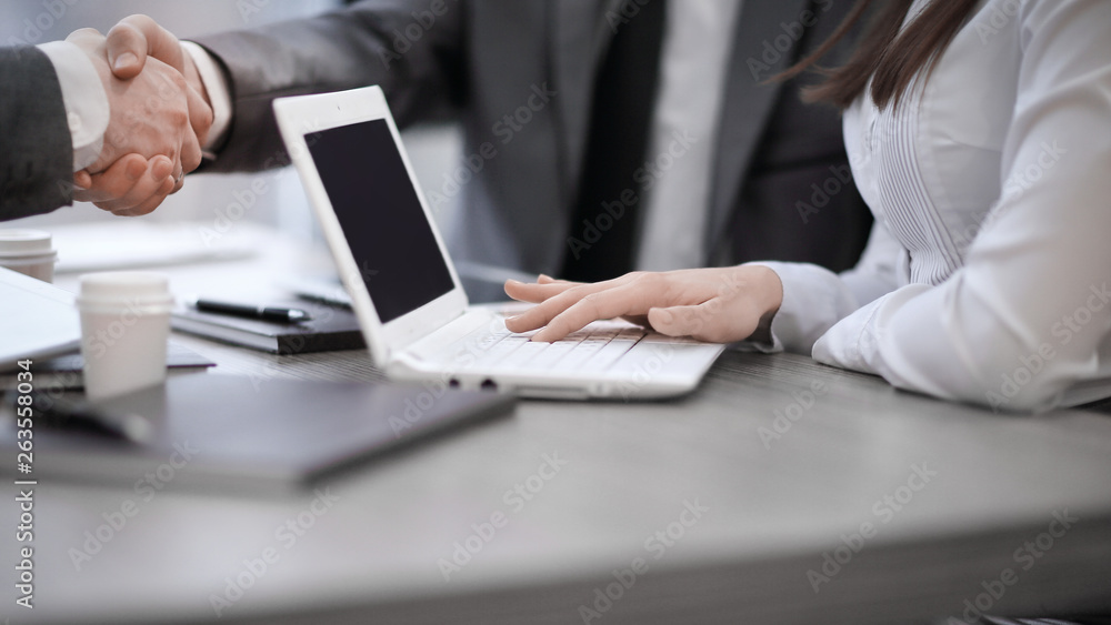 Close up image of business partners handshake over office desk during meeting or negotiation Close up image of business partners handshake over office desk during meeting or negotiation