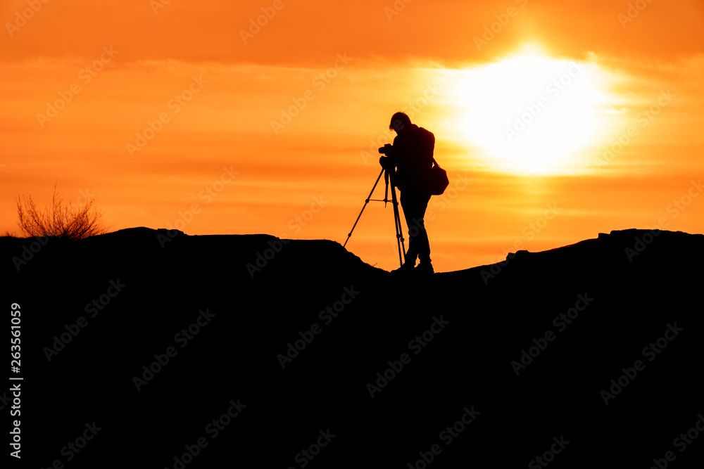 Silhouette of a photographer who shoots a sunset, on top of castle at sunset background.