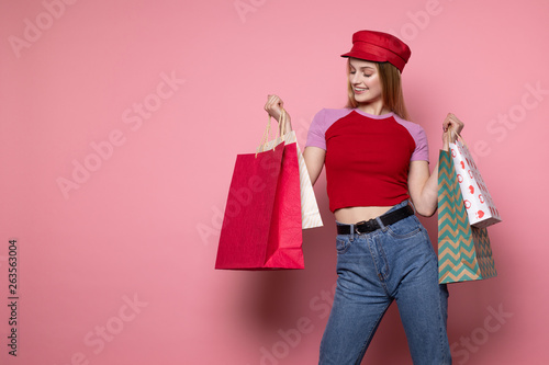Attractive blonde woman in casual clothes and red hat with colorful shopping bags