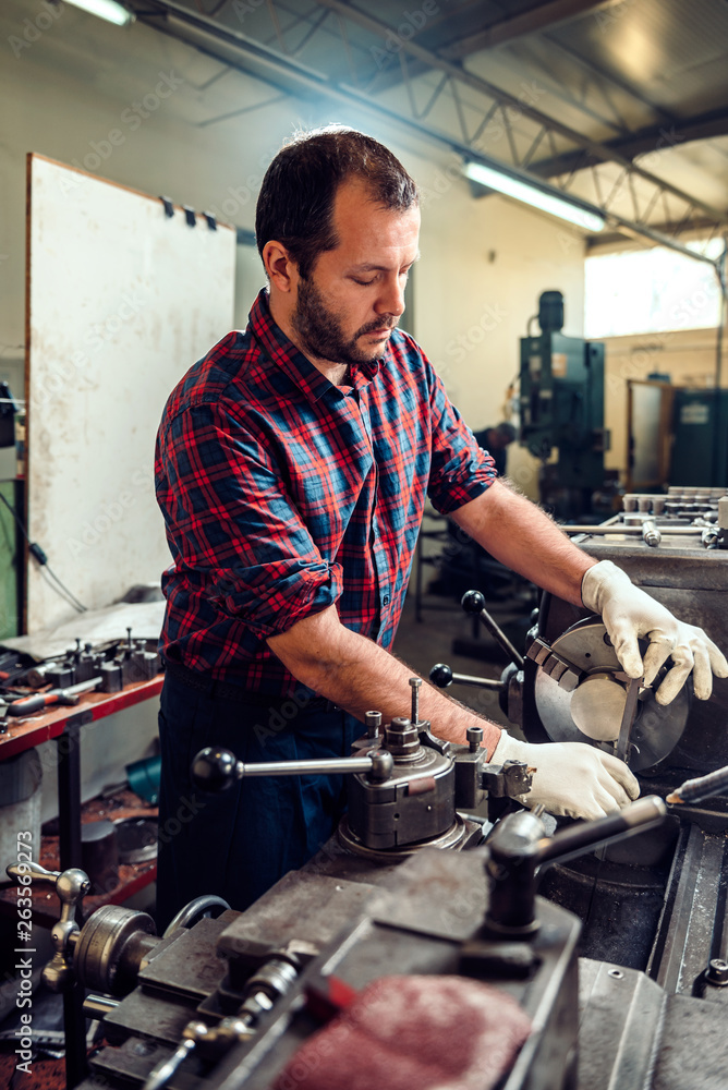 Worker operating lathe machine in the Industrial factory Worker operating lathe machine in the Industrial factory