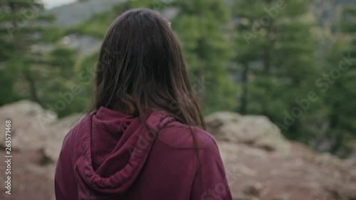 Teenage girl walking in the forest among pine trees