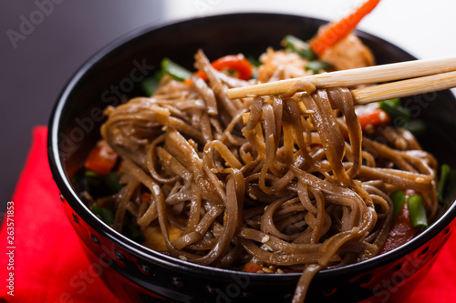 Buckwheat noodle in a black bowl on chicken fillet