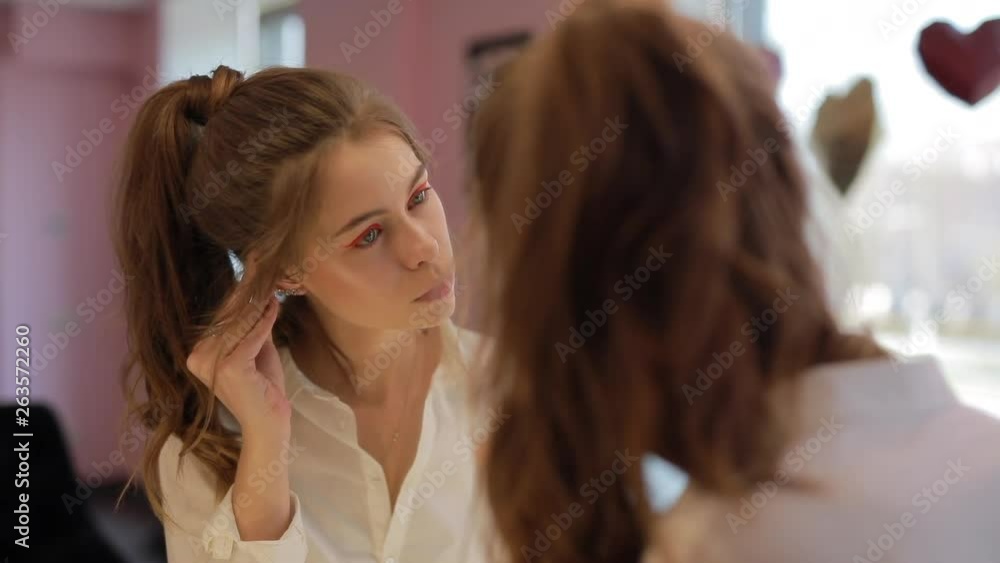 Girl try on earrings in the beauty salon at mirror Girl try on earrings in the beauty salon at mirror