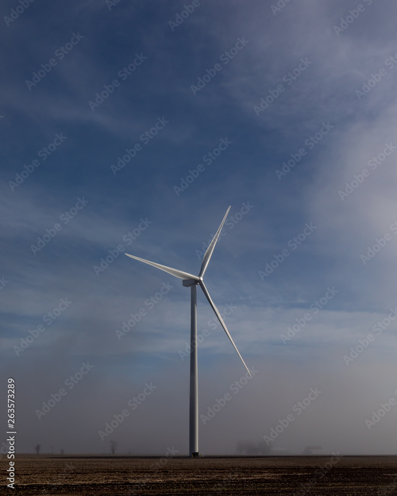 windmill rising above low hanging fog on a sunny morning in the countryside