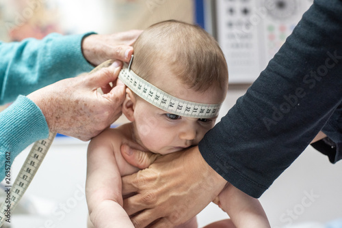 Wall Mural Nurse measuring the cranial perimeter of a baby in a clinic with a tape measure