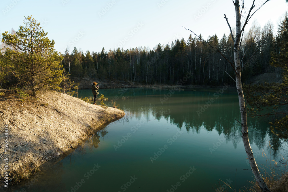 Young woman takes travel photos -Beautiful turquoise lake in Latvia - Meditirenian style colors in Baltic states - Lackroga ezers