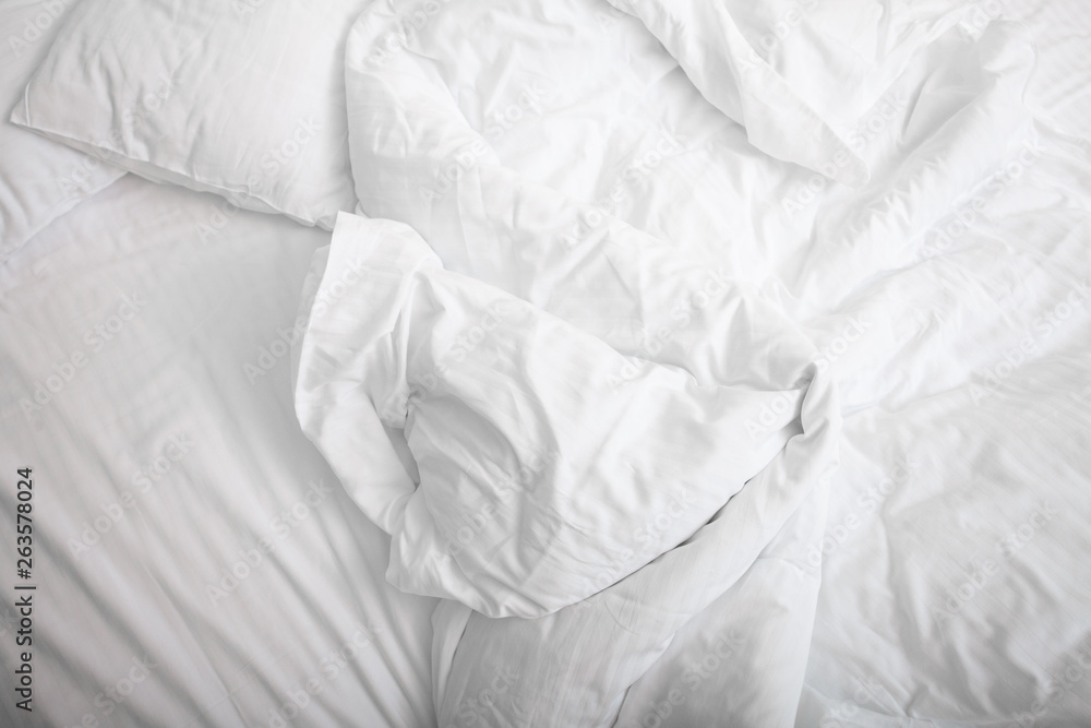View on top of crumpled bed with white linens. Make the bed. Used dirty bedding. Fresh sheets. Crumpled sheets. Bed after sleeping in the morning. Pillow and blanket. Concept. Close up. Copy space. View on top of crumpled bed with white linens. Make the bed. Used dirty bedding. Fresh sheets. Crumpled sheets. Bed after sleeping in the morning. Pillow and blanket. Concept. Close up. Copy space.