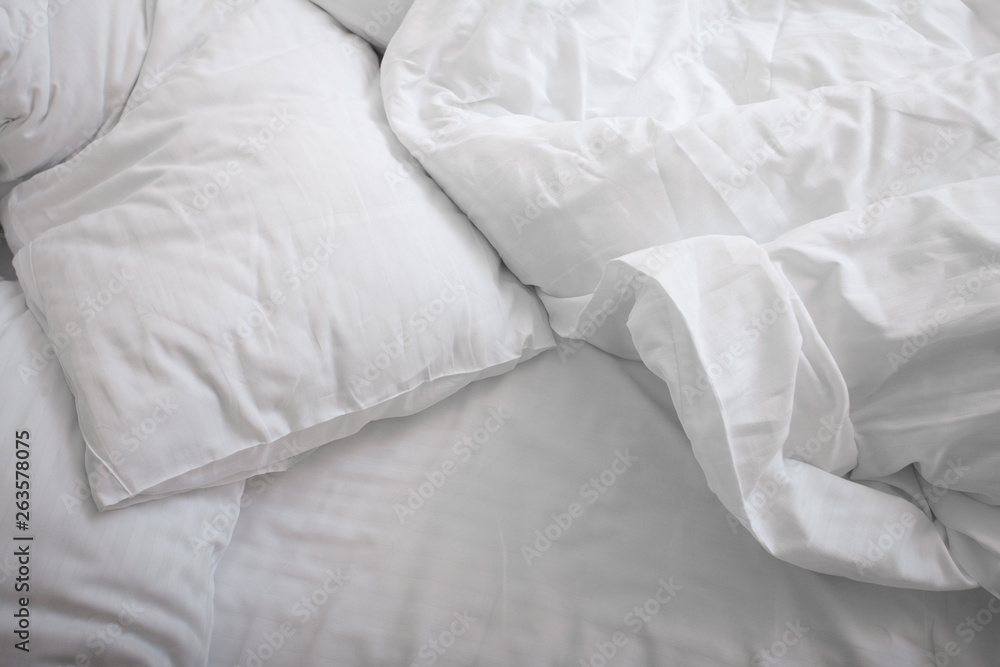 View on top of crumpled bed with white linens. Make the bed. Used dirty bedding. Fresh sheets. Crumpled sheets. Bed after sleeping in the morning. Pillow and blanket. Concept. Close up. Copy space. View on top of crumpled bed with white linens. Make the bed. Used dirty bedding. Fresh sheets. Crumpled sheets. Bed after sleeping in the morning. Pillow and blanket. Concept. Close up. Copy space.