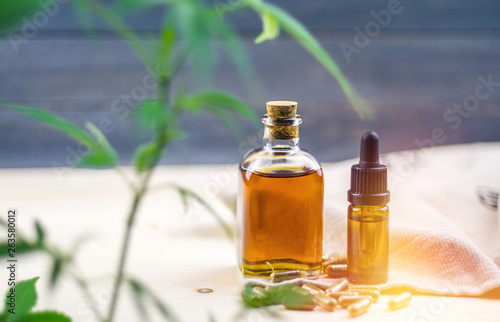 Clear CBD Cannabidiol capsules and cannabis oil on wooden table