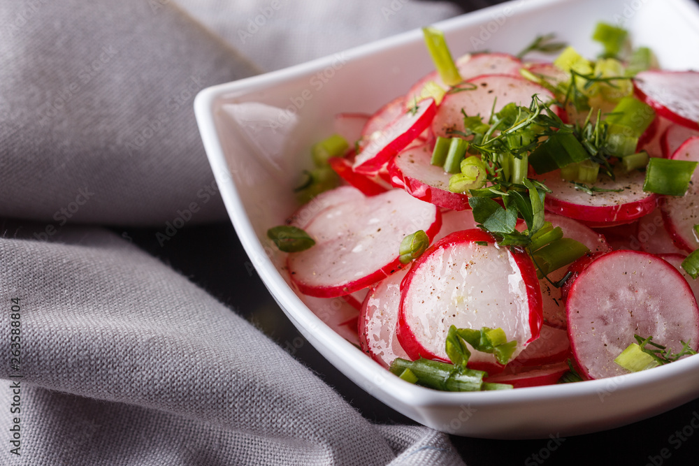 Radish salad in a white bowl on a dark background Radish salad in a white bowl on a dark background