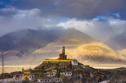 The Maitreya Buddha statue with Himalaya mountains in the background from Diskit Monastery or Diskit Gompa, Nubra valley, Leh Ladakh, Northen India. photo